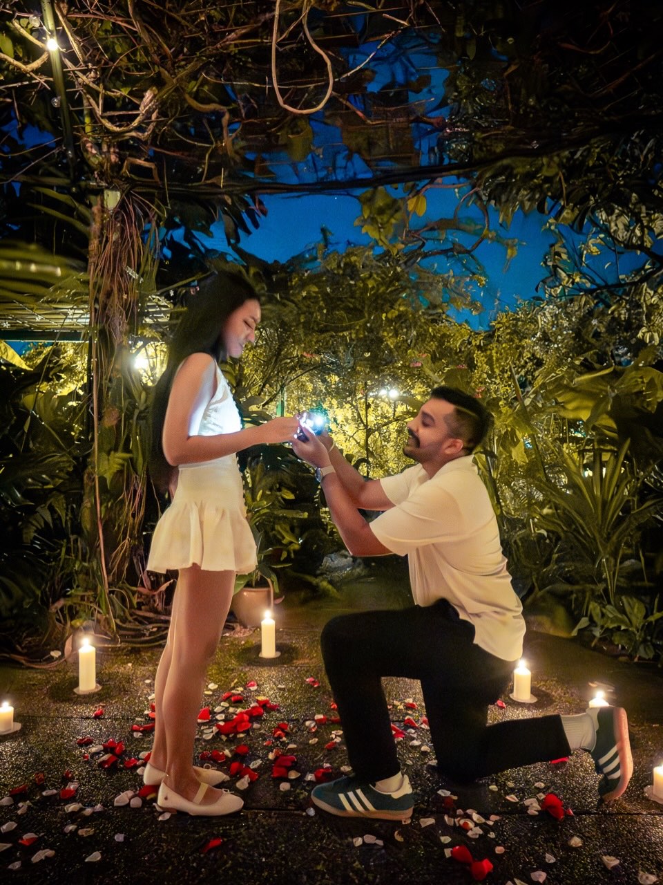 Kevin proposing on one knee surrounded by candles